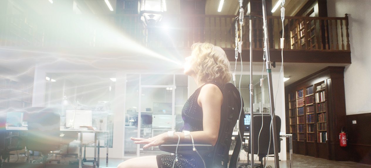 Sitting in a computer chair, Scarlett Johansson is seen with light irradiating out of her mouth in Luc Bresson's 2011 film Lucy.